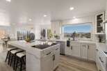 Experience breathtaking mountain views from this stunning modern kitchen, featuring a large island with a built-in stovetop and ample seating.