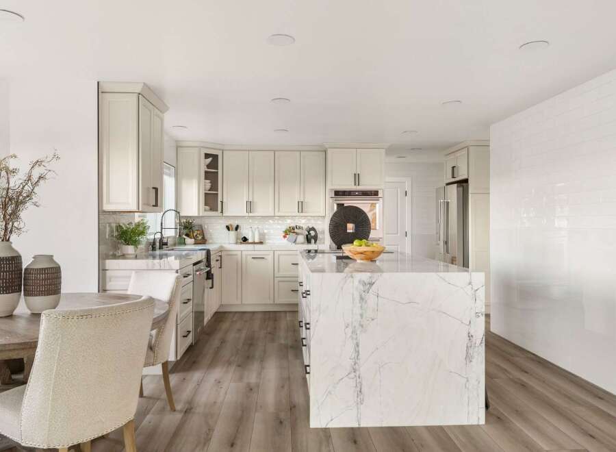 Experience the epitome of modern luxury in this stunning kitchen, featuring sleek white cabinetry and a breathtaking marble-clad island.