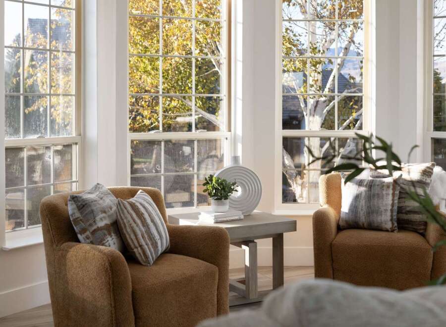 Bathed in natural light, this cozy living space features two plush armchairs adorned with decorative pillows, perfect for relaxing.