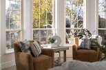 Bathed in natural light, this cozy living space features two plush armchairs adorned with decorative pillows, perfect for relaxing.
