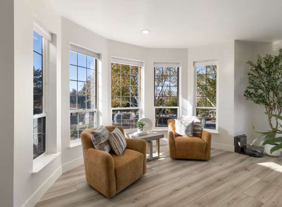 Bathed in natural light, this inviting living space features two plush, caramel-colored armchairs perfect for relaxation.