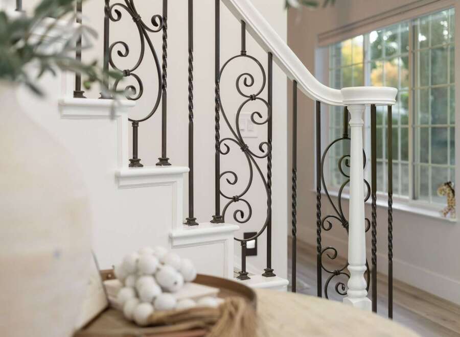 Elevate your home's aesthetic with this stunning staircase featuring elegant wrought iron balusters and a crisp white handrail.