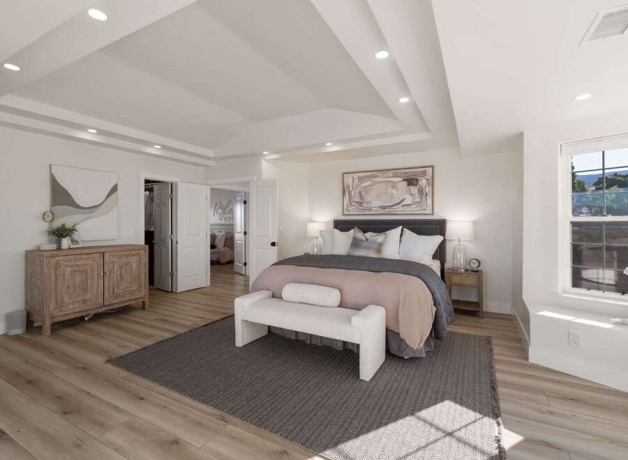 Step into this luxurious master bedroom, featuring a spacious king-size bed adorned with plush pillows and a cozy throw.