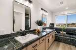 This spacious bathroom boasts a double vanity with elegant black fixtures and a stunning green marble countertop.