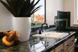 This bathroom features a sleek black faucet and a white sink set against a dark, glossy tiled backsplash and countertop.