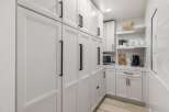 This modern kitchen features sleek white cabinetry with black hardware, offering ample storage and a clean aesthetic.