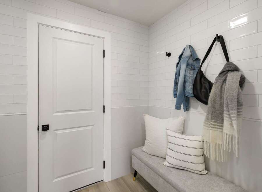 This entryway features a modern white door with a black knob, complemented by white subway tile walls.