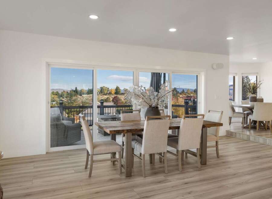 Experience breathtaking views from this stunning dining area, featuring a rustic wooden table and comfortable upholstered chairs.