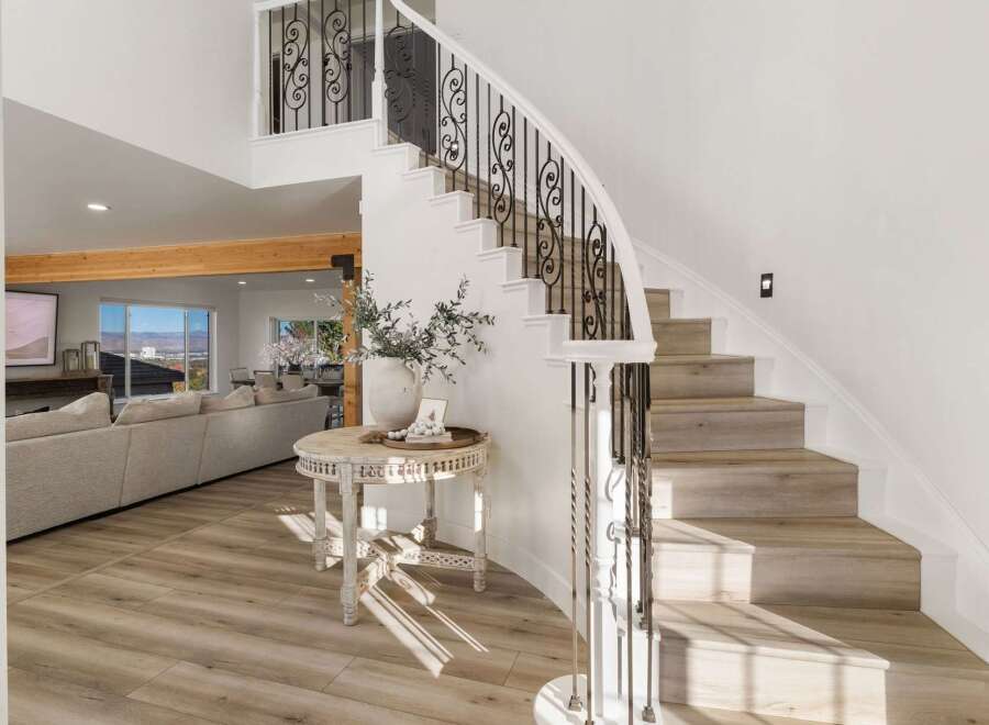 Step into luxury with this grand curved staircase, featuring elegant wrought iron railings and light wood treads that beautifully complement the surrounding modern interior.