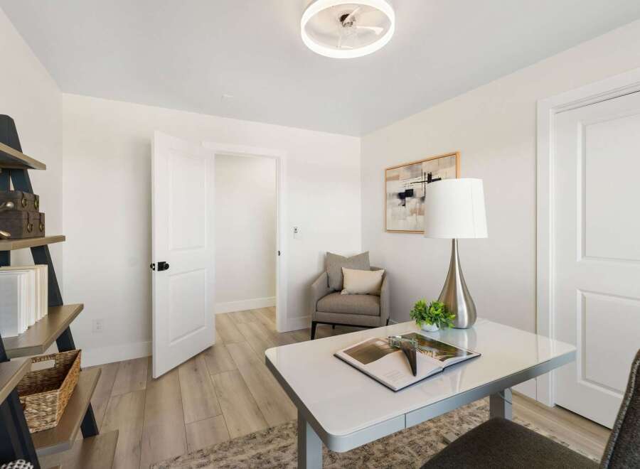 This home office features a sleek white desk with a modern lamp and a decorative plant, creating a productive workspace.