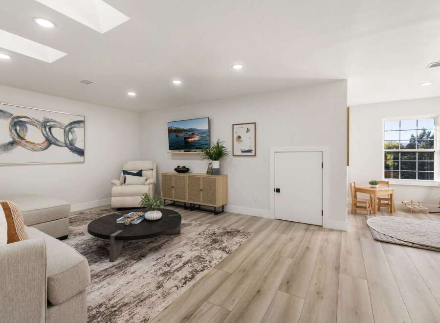 This spacious living room features a large abstract painting, a comfortable recliner, and a modern media console.