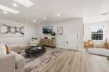 This spacious living room features a large abstract painting, a comfortable recliner, and a modern media console.