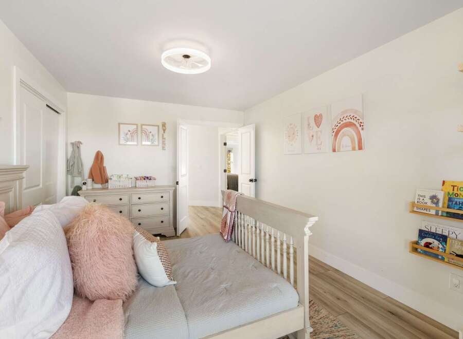 This charming bedroom features a cozy bed adorned with plush pink pillows and a soft gray comforter, perfect for relaxation.
