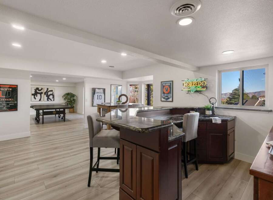 This finished basement offers a fantastic entertainment space, complete with a full bar featuring granite countertops and comfortable bar stools.