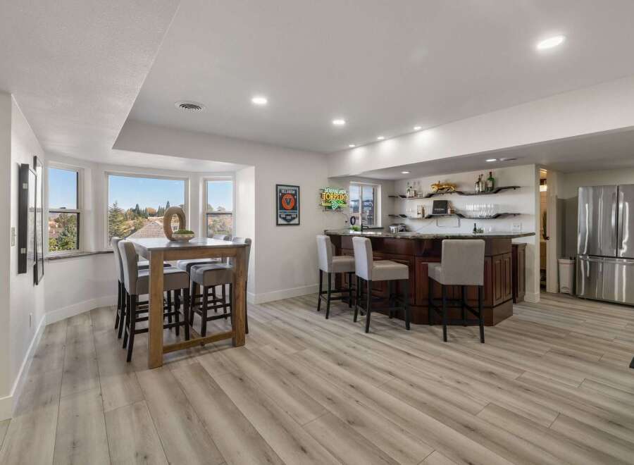 This spacious basement features a modern dining area with a wooden table and bar stools, perfect for casual meals or entertaining guests.