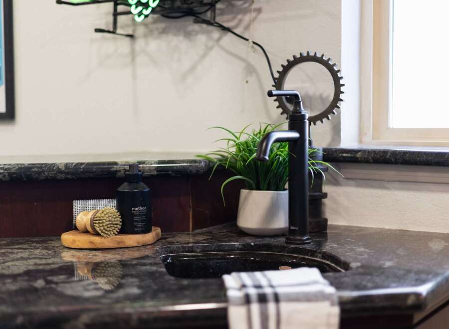 This modern bathroom features a sleek black faucet and a granite countertop, adding a touch of sophistication.