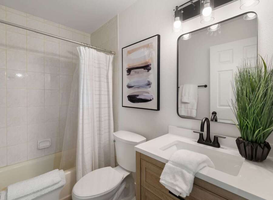 This modern bathroom features a clean white tiled shower and tub combo, complemented by a white fabric shower curtain.