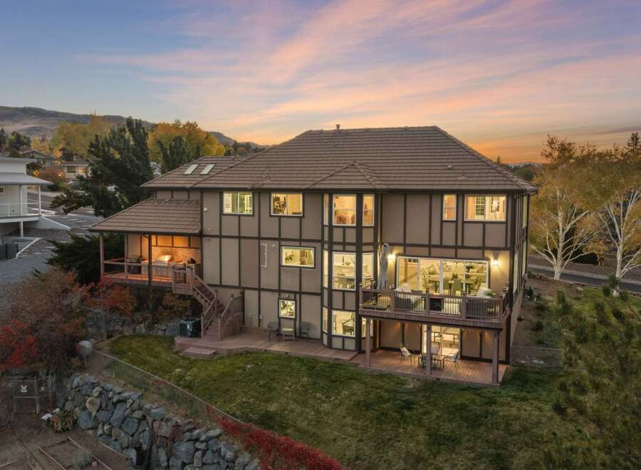 This stunning multi-level home boasts an expansive backyard perfect for entertaining, featuring multiple decks and a covered outdoor kitchen area.