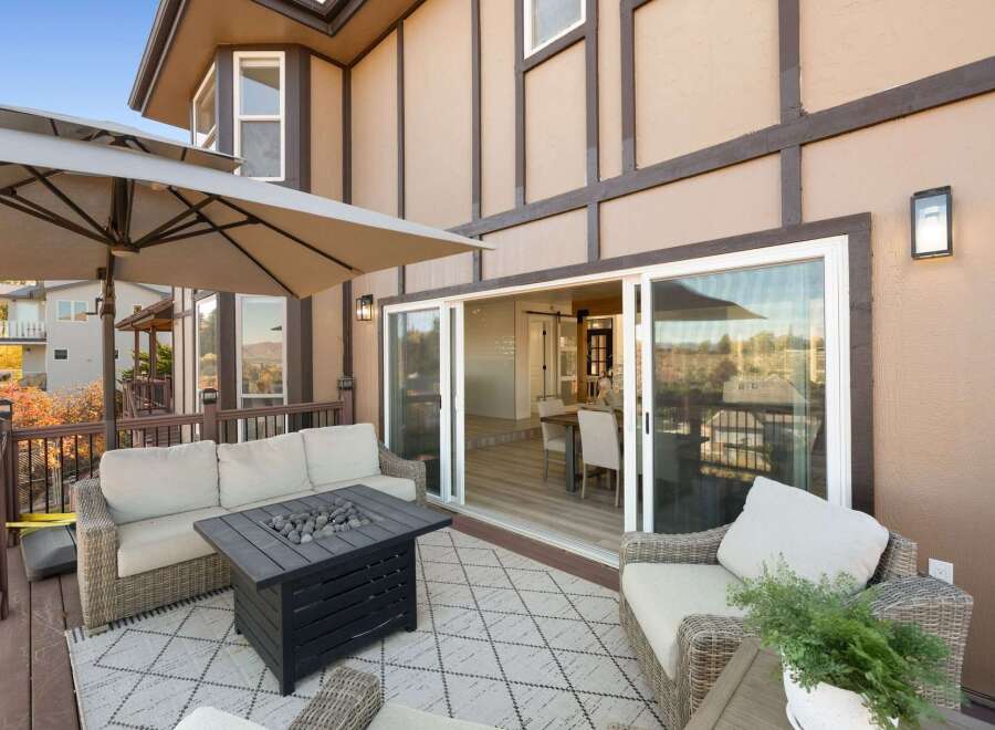 Enjoy outdoor living on this spacious deck, complete with a comfortable seating area and a modern fire pit table.