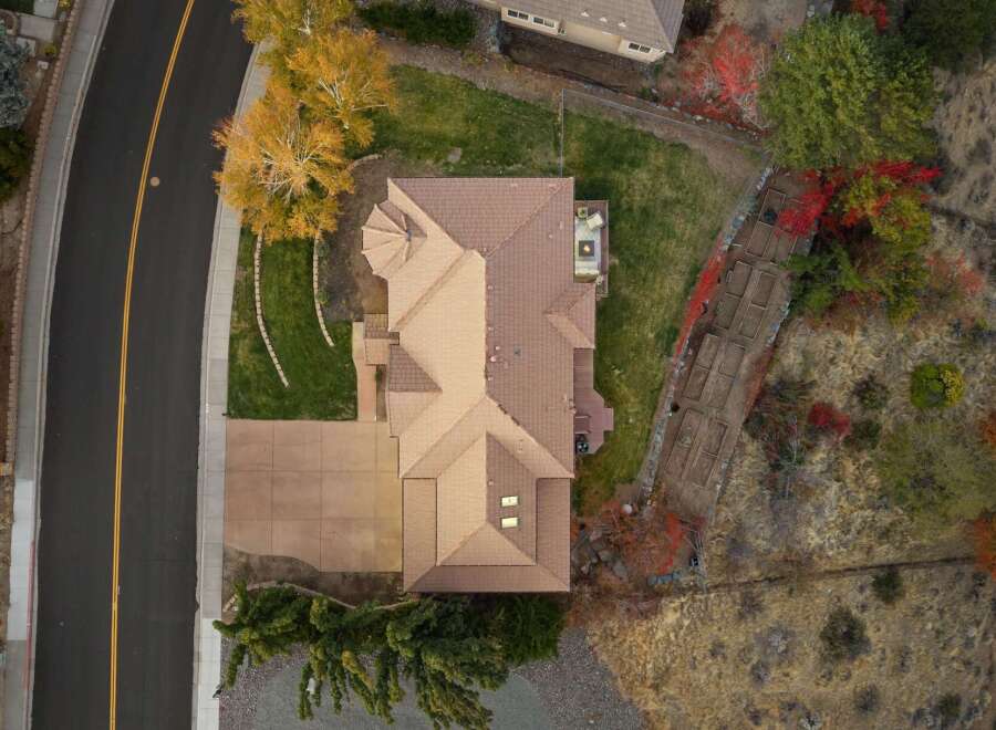 Experience luxury living in this stunning aerial view of a spacious home featuring a large, well-maintained lawn and a paved driveway.