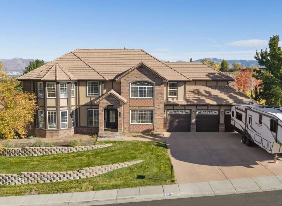 This stunning multi-story home boasts a beautiful brick and stucco exterior, complemented by a tile roof and numerous large windows that allow for ample natural light.