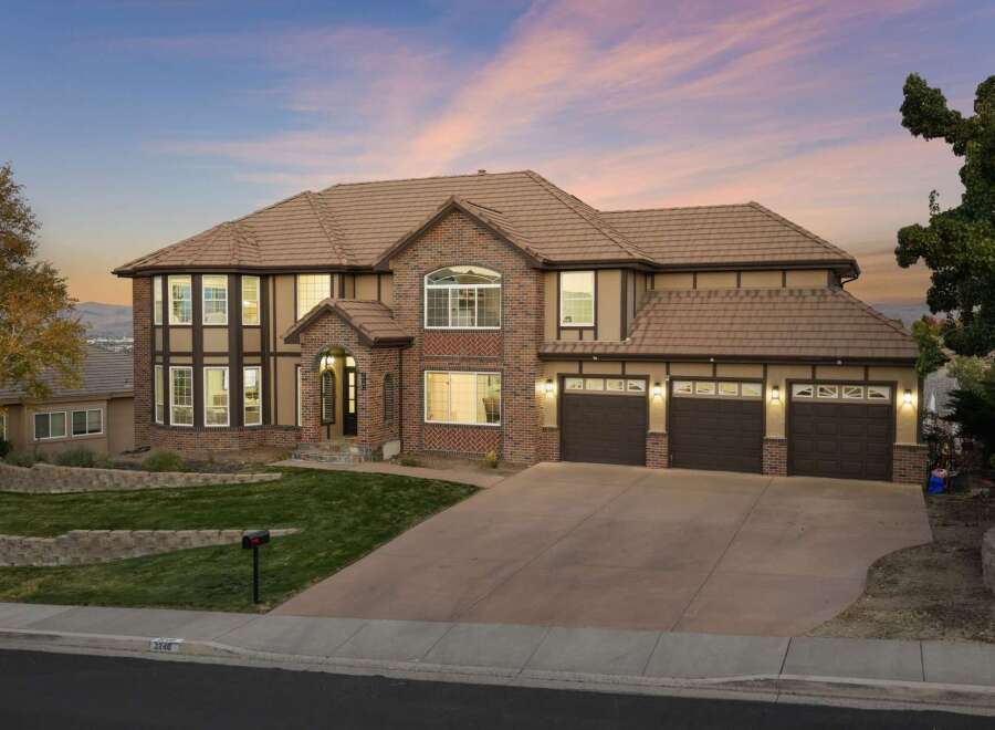 This stunning multi-story home boasts a beautiful brick and stucco exterior, complemented by a warm, earthy color palette and a classic tile roof.