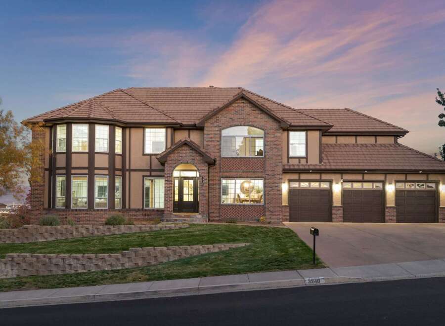 This stunning two-story home boasts a striking architectural design with a combination of brick and stucco exterior, complemented by a warm, inviting color palette.