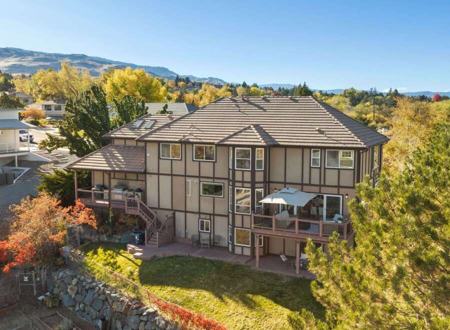 This stunning multi-story home boasts a spacious backyard perfect for entertaining, featuring multiple decks and a built-in grill area.