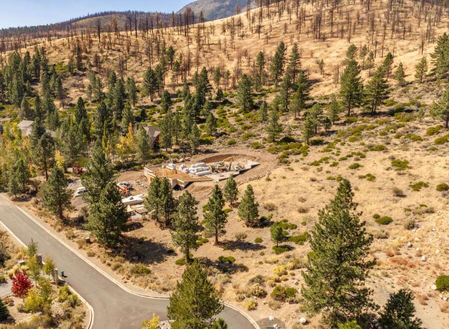 Discover this stunning property featuring a new home construction in progress, nestled amidst a picturesque landscape of pine trees and rolling hills.
