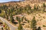 Discover this stunning property featuring a new home construction in progress, nestled amidst a picturesque landscape of pine trees and rolling hills.