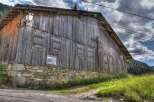 Rustic wooden barn for sale, boasting a charming stone foundation and picturesque mountain views.