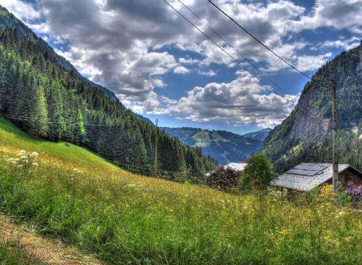 Secluded mountain chalet with solar panels, nestled in a lush alpine meadow.