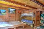 Rustic wooden cabin with bunk beds and scenic wall art.