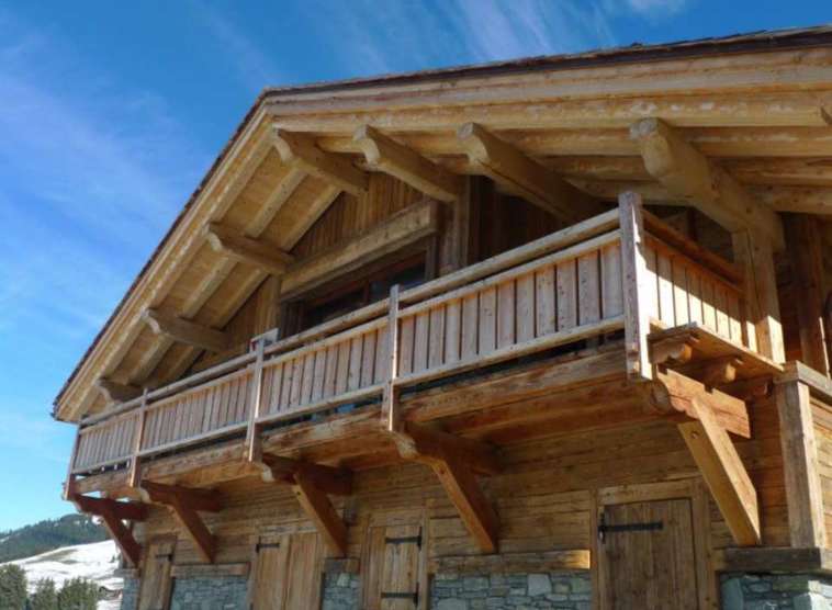 This stunning chalet boasts a beautiful wooden exterior with a large balcony, perfect for enjoying the mountain views.
