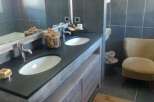 Relax in this charming bathroom boasting a rustic double vanity with a sleek dark countertop.