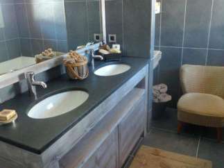 Relax in this charming bathroom boasting a rustic double vanity with a sleek dark countertop.