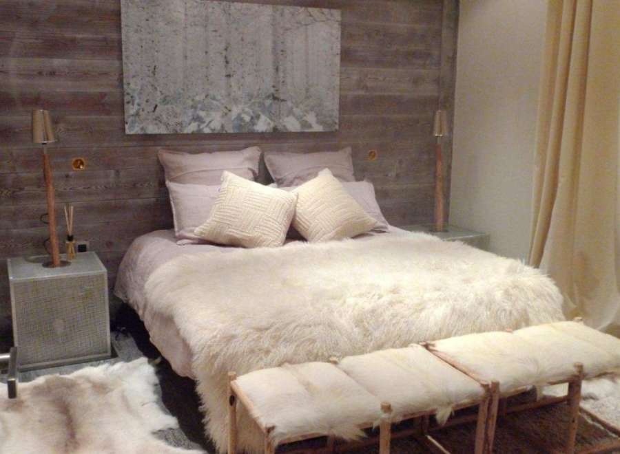 Cozy up in this luxurious bedroom featuring a plush sheepskin throw and handcrafted wooden stools.
