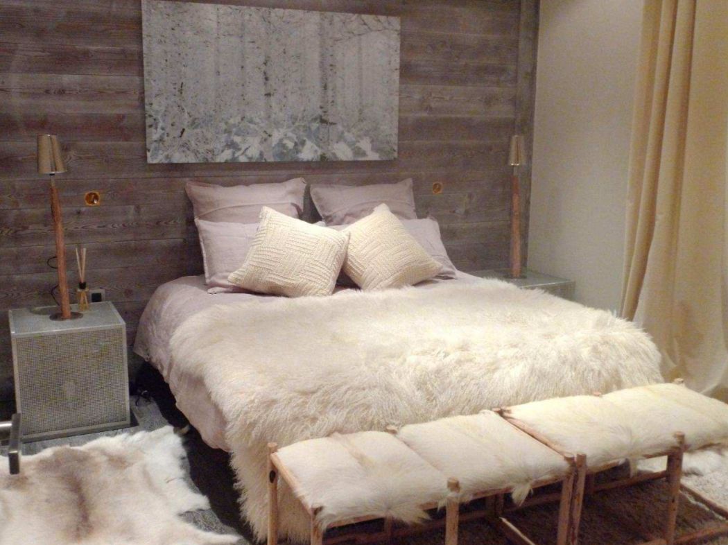 Cozy up in this luxurious bedroom featuring a plush sheepskin throw and handcrafted wooden stools.
