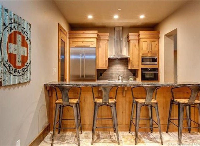 This stunning kitchen boasts a rustic-chic design with wood cabinetry, stainless steel appliances, and a granite countertop breakfast bar.