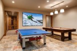 This stunning game room boasts a large projector screen perfect for movie nights, along with a ping pong table and pool table for entertainment.