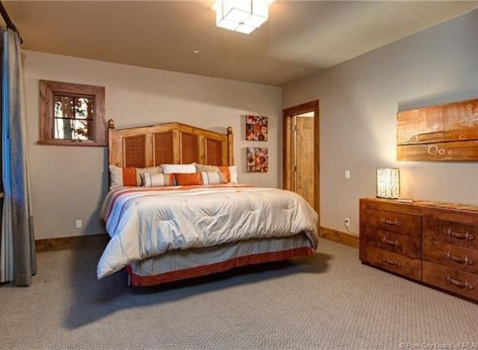 This stunning bedroom boasts a king-size bed, plush bedding, and a gorgeous wooden headboard.