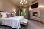 This luxurious bedroom boasts a cozy fireplace, large windows offering stunning views, and a plush bed with high-end linens.