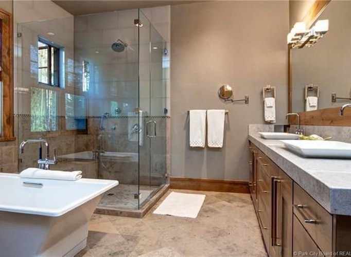 Luxurious bathroom boasts a spacious glass shower, soaking tub, and double vanity with ample counter space.