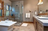 Luxurious bathroom boasts a spacious glass shower, soaking tub, and double vanity with ample counter space.
