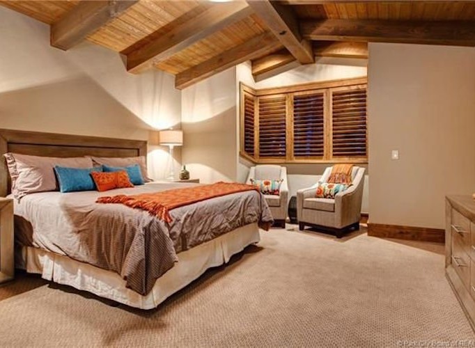 This luxurious bedroom boasts a king-size bed, plush carpet, and stunning wood-beamed ceilings.