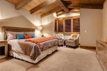 This luxurious bedroom boasts a king-size bed, plush carpet, and stunning wood-beamed ceilings.