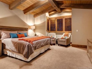 This luxurious bedroom boasts a king-size bed, plush carpet, and stunning wood-beamed ceilings.