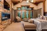 This luxurious bedroom boasts a stunning stone fireplace, large windows showcasing breathtaking views, and a comfortable chaise lounge perfect for relaxation.