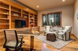 This stunning home boasts a spacious office with custom built-in shelving, hardwood floors, and a large window offering abundant natural light.