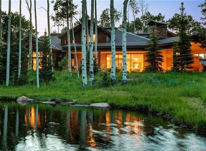 Luxury mountain home nestled amongst aspen trees, offering stunning views and a serene pond.